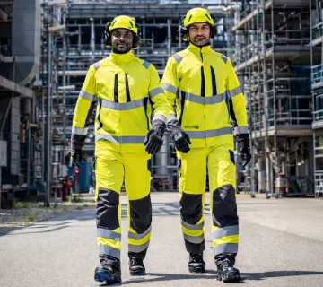 Workers wearing high visibility protective uniforms and safety helmets in an industrial work environment ”