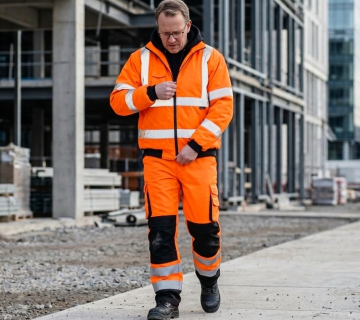 Worker wearing reflective safety vests and high visibility clothing at a construction site