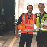 Industrial workers in hi vis safety vests and helmets at a factory site