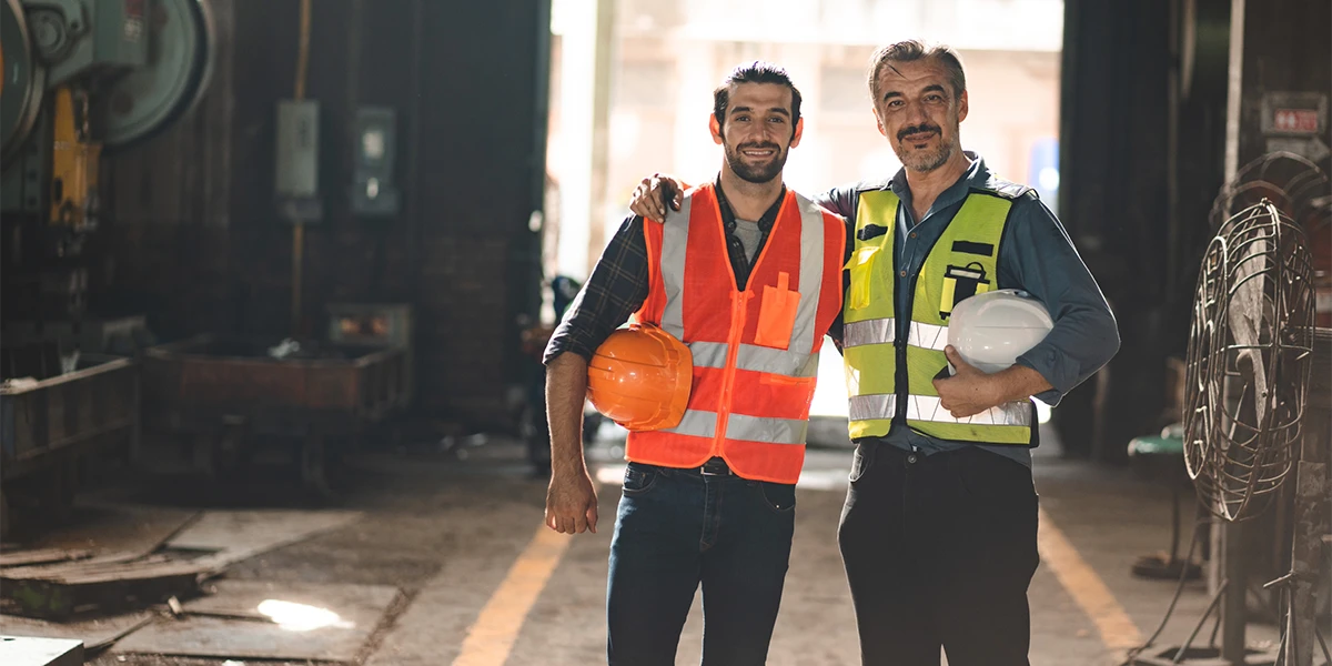 Industrial workers in hi vis safety vests and helmets at a factory site